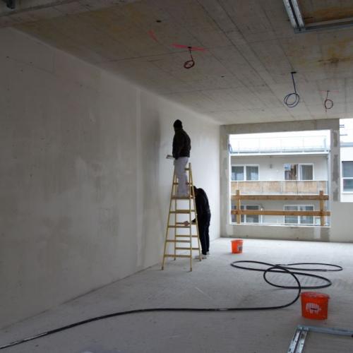 Bauarbeiter vor glatter Wand in neuem Klassenraum
