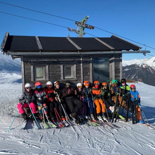 Jugendliche mit Schiausrüstung vor einer Hütte