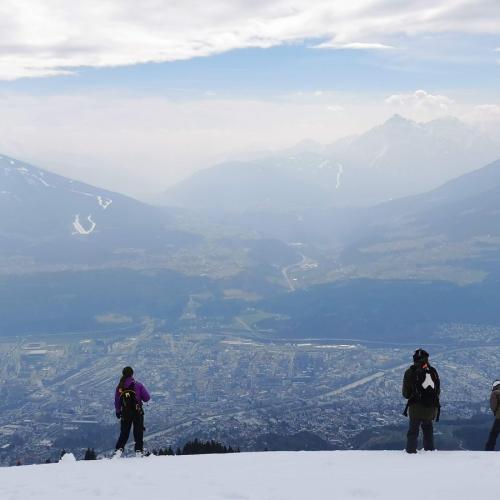 Schüler:innen blicken von einem schneebedeckten Berg auf die Stadt Innsbruck im Tal