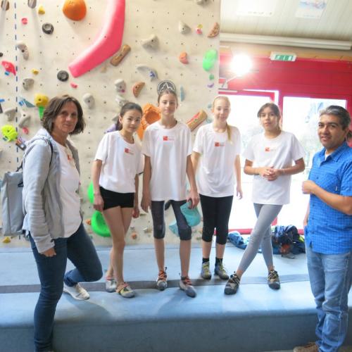 Vier Kinder und Lehrerin vor einer Kletterwand