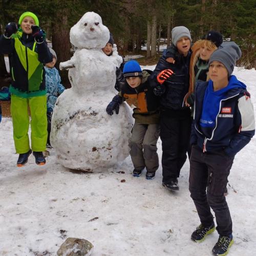 Kinder mit Schneemann in der Mitte