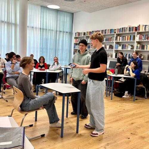 Schüler in der Bibliothek, sitzend und stehend neben Tisch