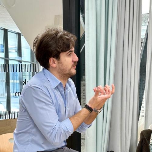 Der Autor Gigi Colasanto sitzt auf einem Tisch und gestikuliert