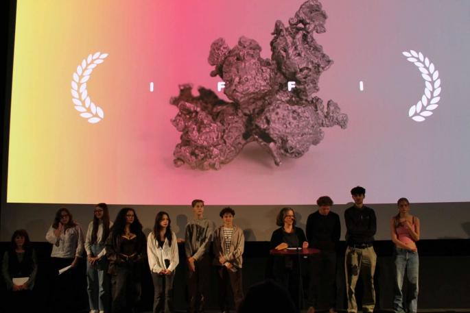 Schüler:innen vor einer Leinwand mit der Aufschrift "IFFI"