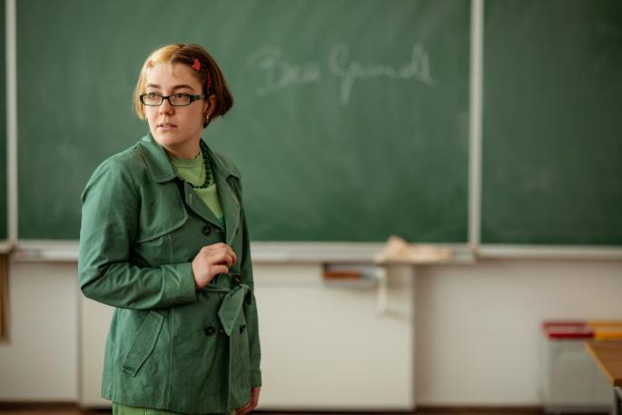 Grün gekleidete Frau vor grüner Tafel