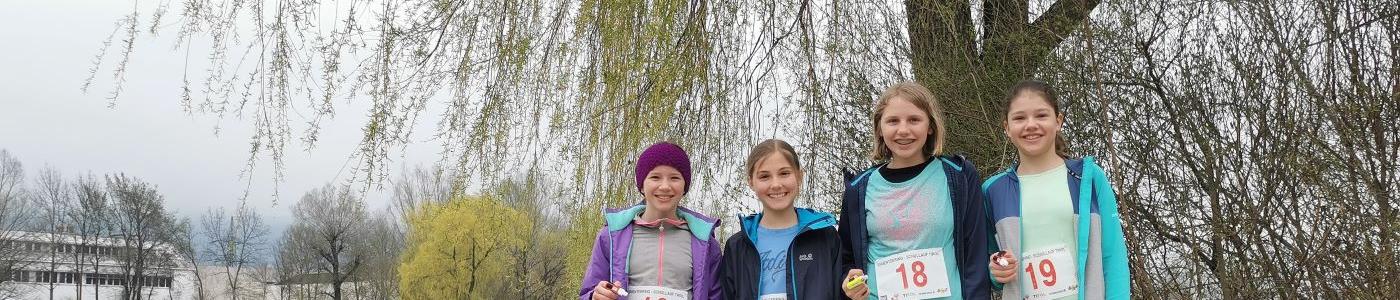 Vier Mädchen mit Startnummern vor einem Baum