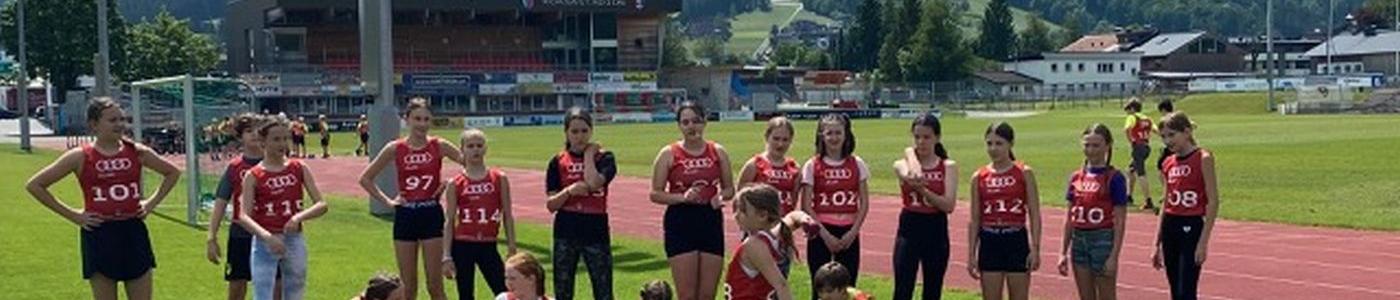 Kinder in roter Sportkleidung auf einem Sportplatz