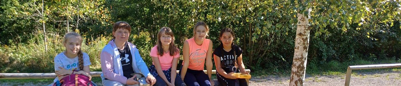 Fünf Mädchen sitzen auf einer Bank bei einem Spielplatz