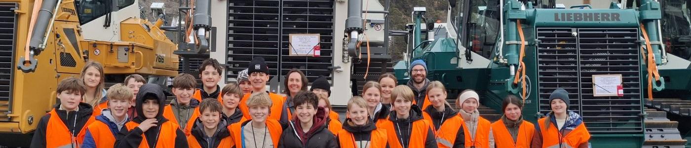 Schüler:innengruppe vor Planierraupen von Liebherr