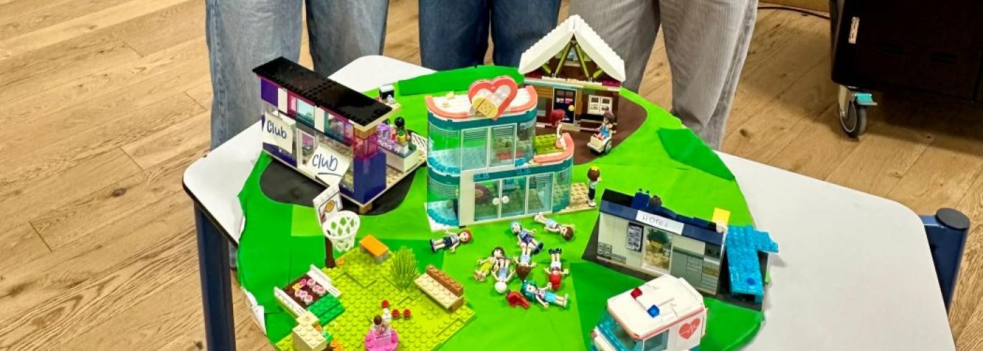 Drei Schülerinnen präsentieren eine LEGO-Landschaft 