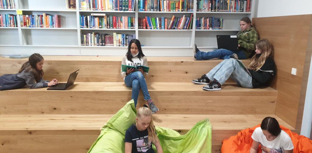 Holzstufen, auf denen Kinder sitzen und lesen